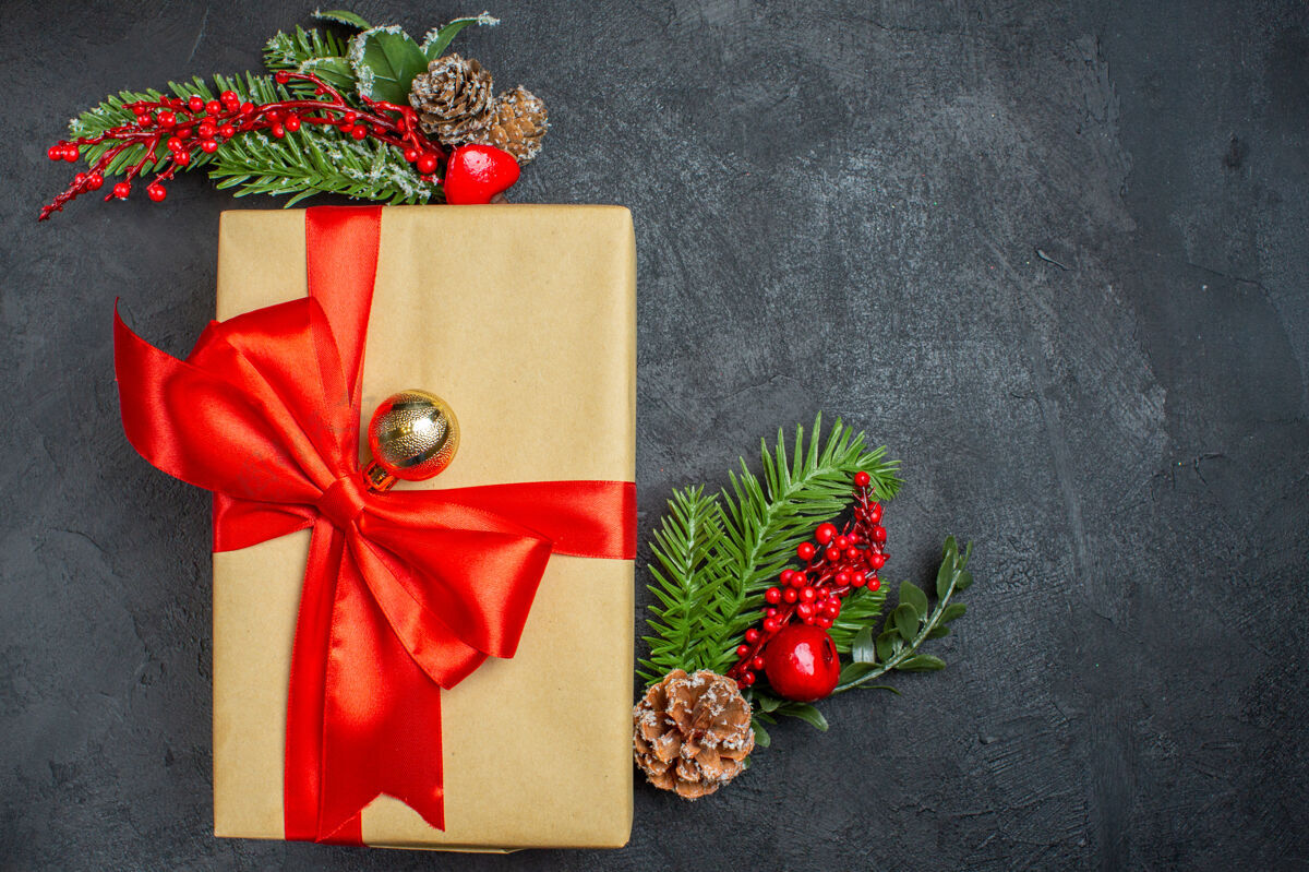 蝴蝶结圣诞背景与蝴蝶结形丝带和杉木枝装饰配件的右侧在一个黑暗的桌子上美丽的礼物花束壁板右边