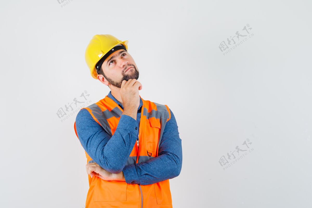 建筑工人年轻的建筑工人穿着衬衫 背心 头盔抬头望去 面带沉思 俯瞰前方安全工作男人