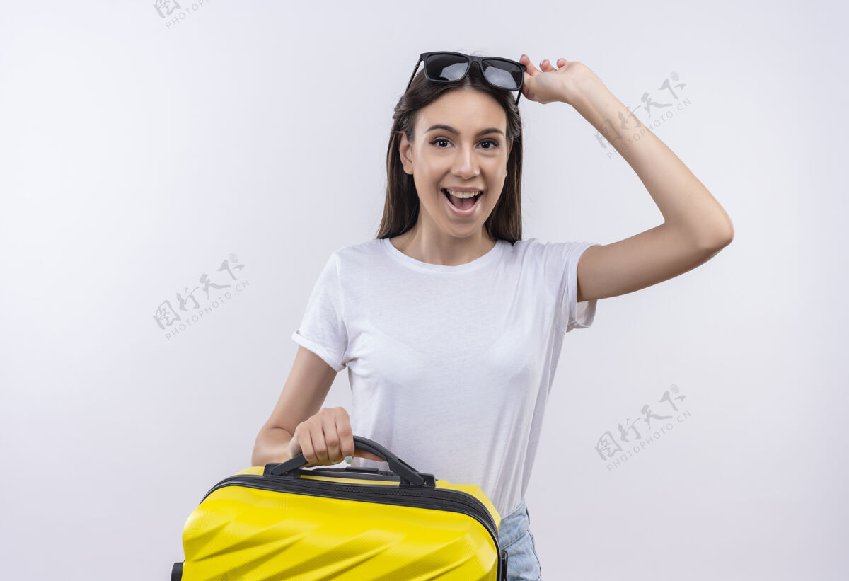 旅行者年轻漂亮的旅行女孩抱着手提箱积极快乐地笑着积极向上抱着微笑