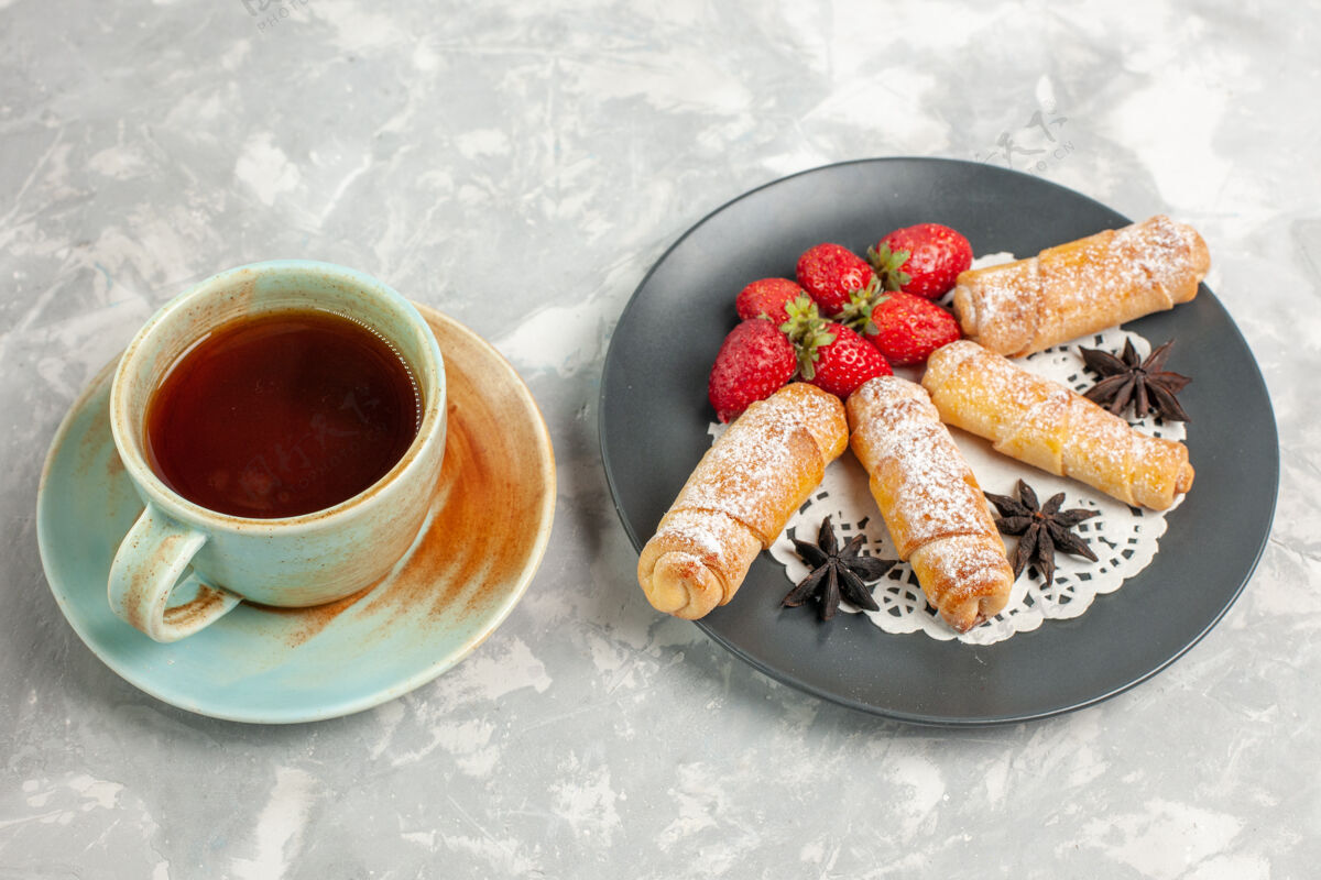 美味草莓和一杯茶的糖粉百吉饼的正面图百吉饼早餐饼干