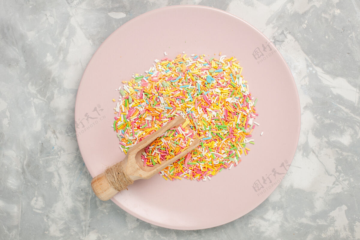 美食白色桌子上盘子里五颜六色的小糖果顶视图勺子勺子食物