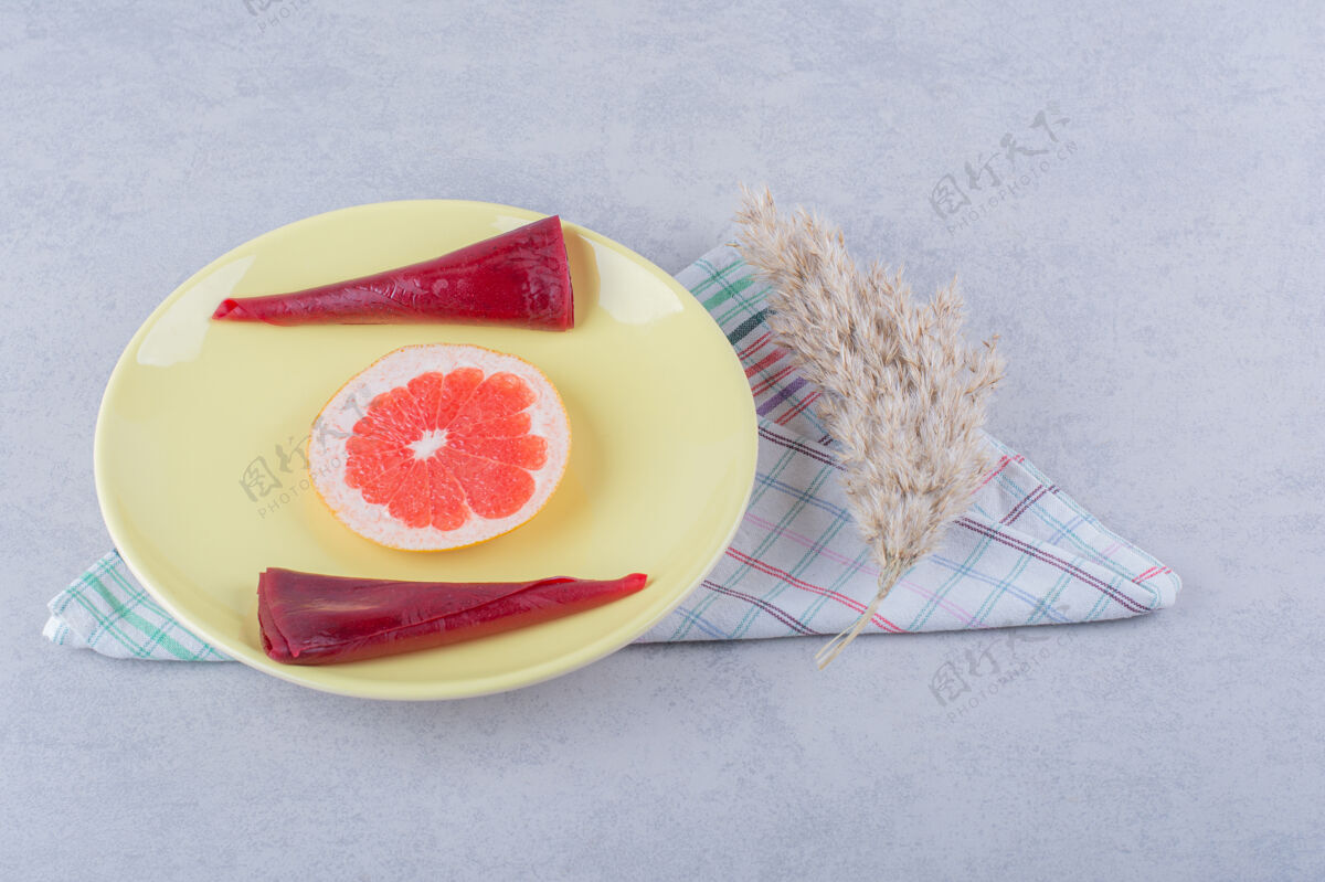 新鲜石桌上放着一盘黄色的干果浆和葡萄柚切片葡萄柚甜