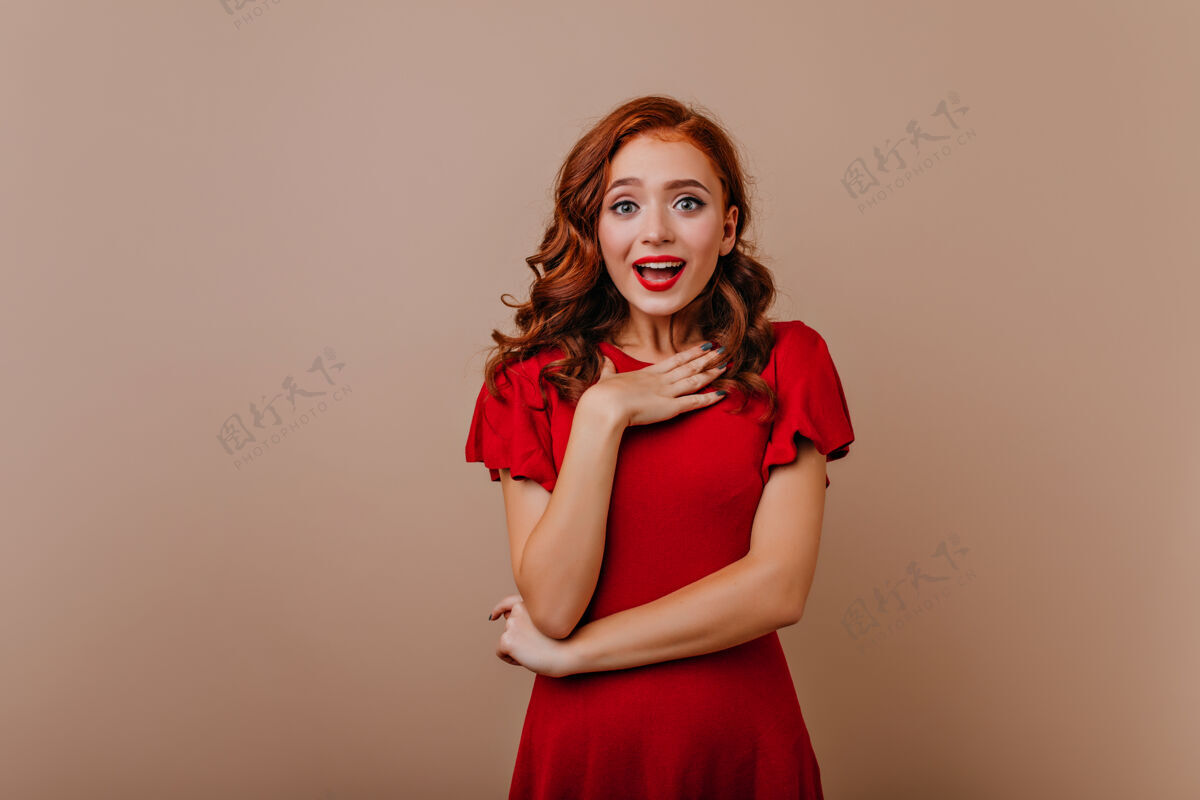 发型惊艳可爱的长发女孩站在明亮的墙上优雅的欧洲红衣女人摆姿势兴奋Swoosh情绪