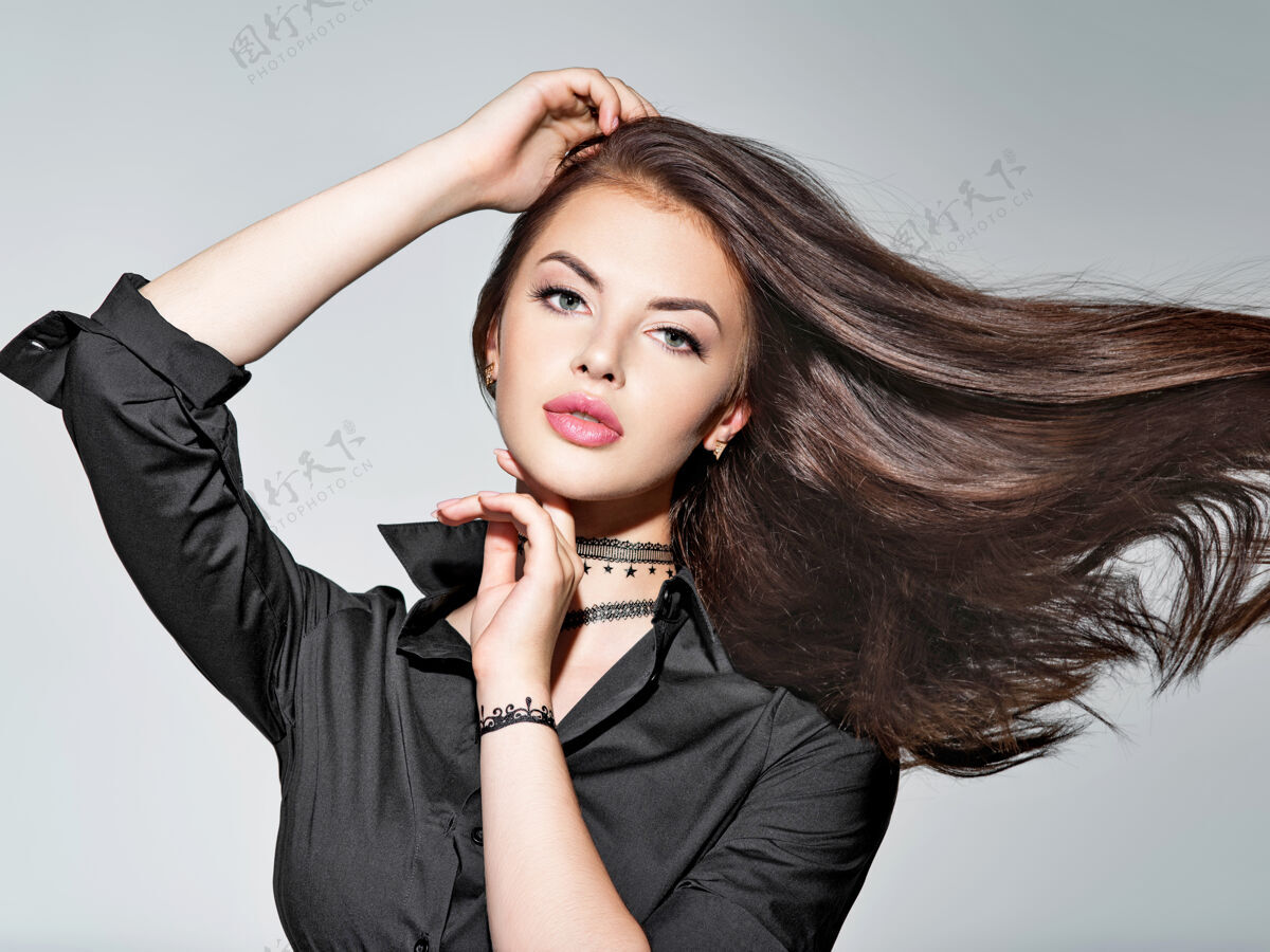 肖像一个留着长直发的年轻女人-在摄影棚一个迷人的黑发女孩的肖像穿着黑色衬衫的时装模特性感的女模特女孩黑发黑色