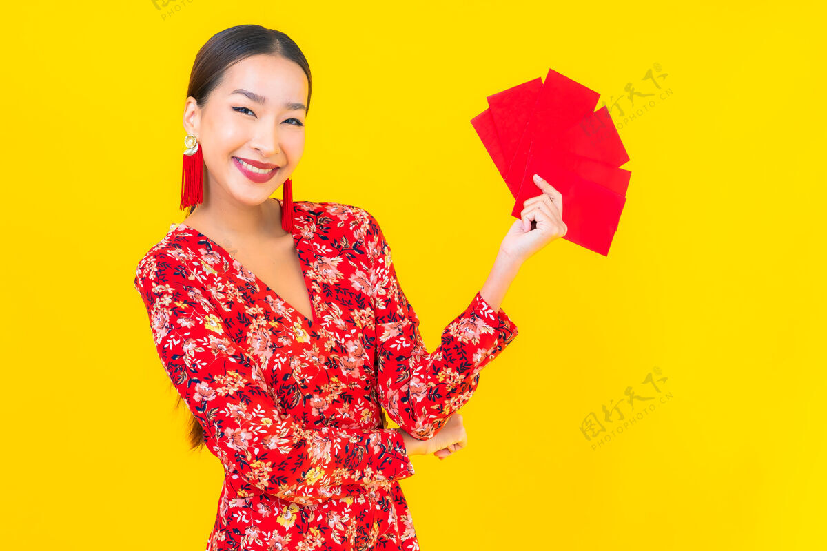 红包在黄色的墙上画一幅美丽的亚洲年轻女子拿着红包人东方人模特