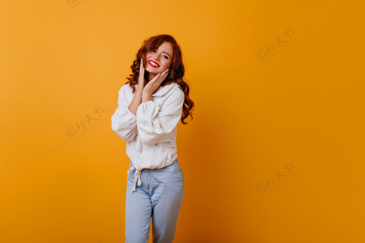 成人迷人的长发女孩摆出可爱的微笑优雅的白人小姐站在黄色的墙上室内时尚积极