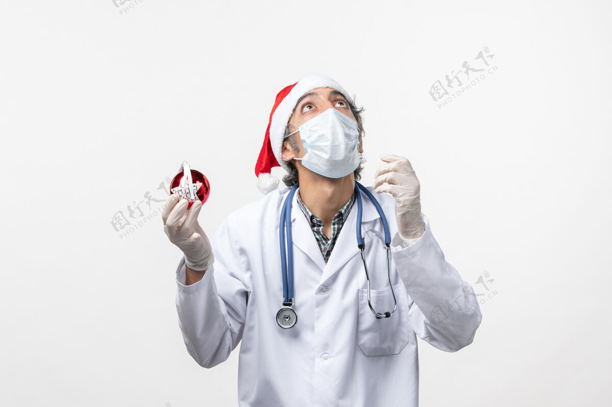 外套正面图戴着面具的男医生带着玩具在白墙上健康的柯维德假日病毒医药病毒医疗器械