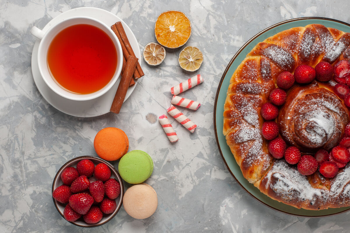 饼干顶视图一杯茶与麦卡龙和草莓派在浅白色的表面营养品桌子生的