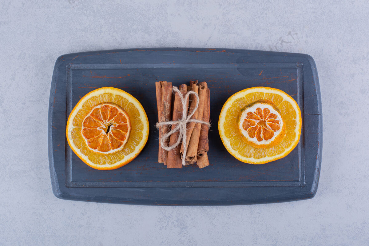 健康橘子片放在深色的木板上 配上香浓的肉桂条棒调味品食用