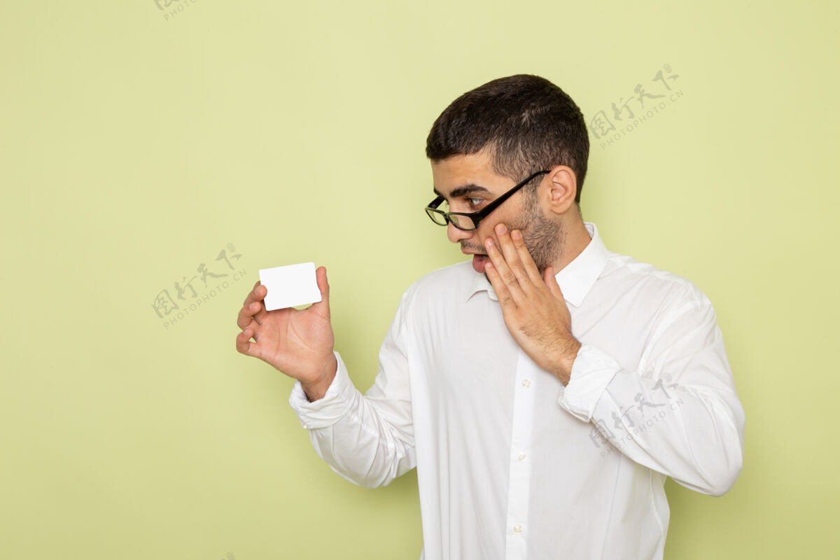 工作身穿白衬衫 手持塑料卡的男性上班族在浅绿色墙上的正面照片实验室外套工作办公室