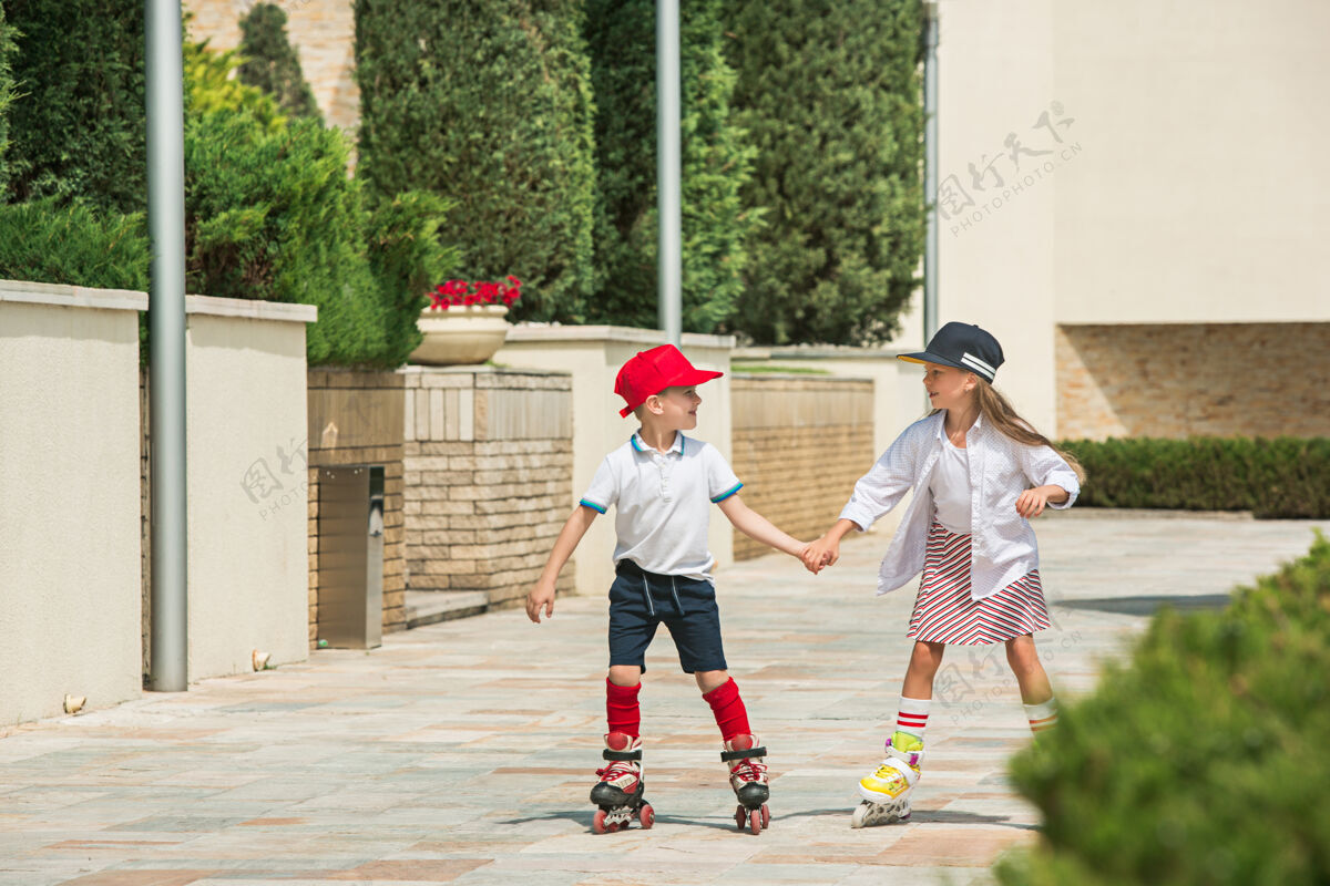 户外在公园里 一对迷人的年轻夫妇穿着溜冰鞋一起滑冰年轻的白人男孩和女孩女性情侣活跃