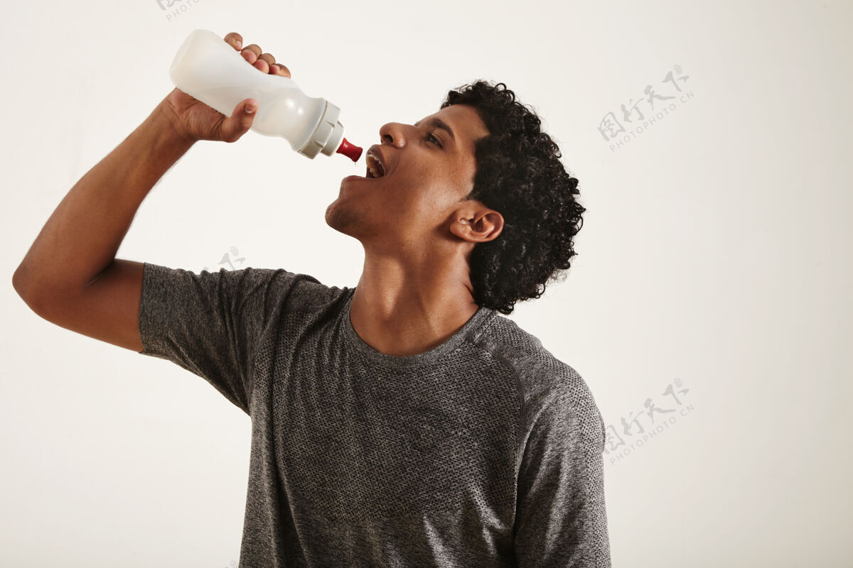 健身年轻健康微笑的黑人男子从一个运动瓶里喝水 嘴巴张开 孤立在白色上持有美国人肌肉