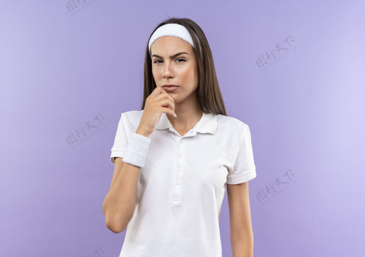 女孩体贴漂亮的运动女孩戴着头带和腕带把手放在下巴上孤立的紫色空间漂亮体贴戴