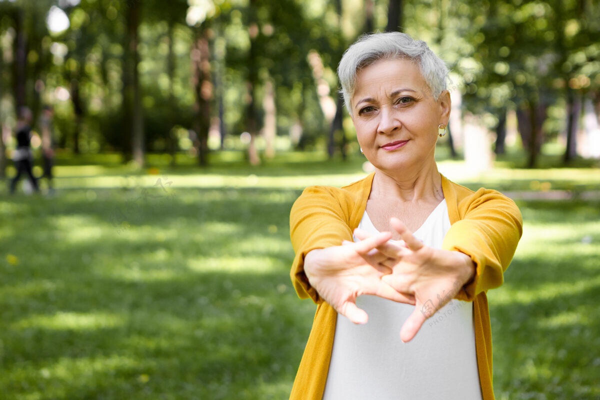 户外户外图片迷人的白发退休妇女伸展手臂肌肉 在公园晨练前热身人 运动 健康 健身 衰老 娱乐和活动的概念活动老年人老年人