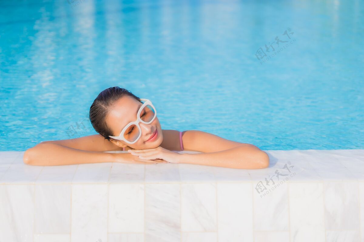 热带肖像美丽的亚洲年轻女子放松休闲围绕室外游泳池与海海洋乐趣帽子