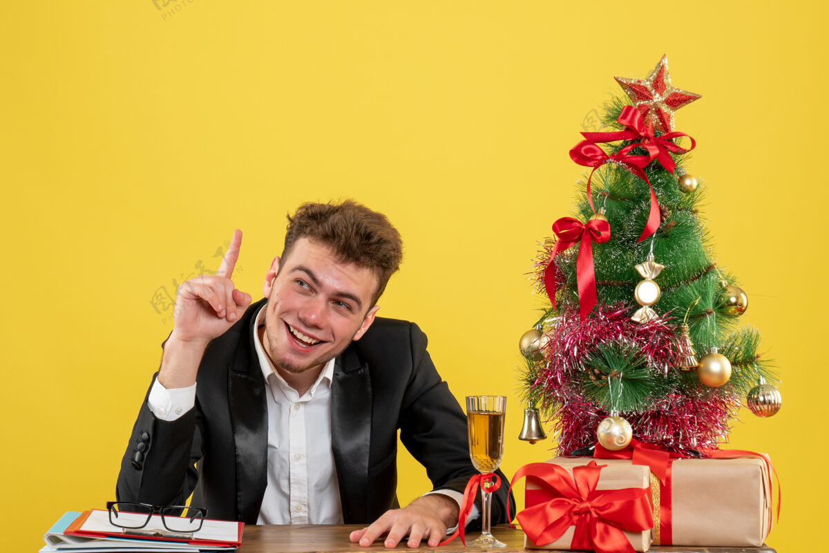 圣诞节正面图：坐在黄色工作台后面的男工人礼物年份工作