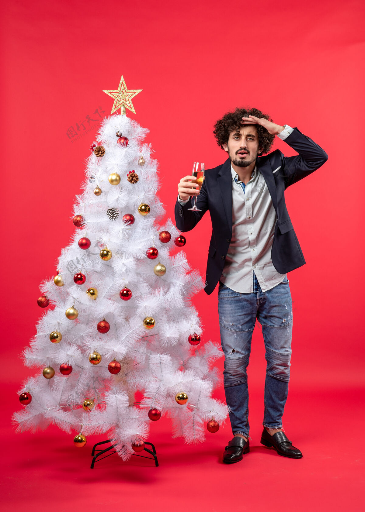 站着圣诞节庆祝活动与留胡子的年轻人用酒专注于一些东西仔细男人庆祝礼物