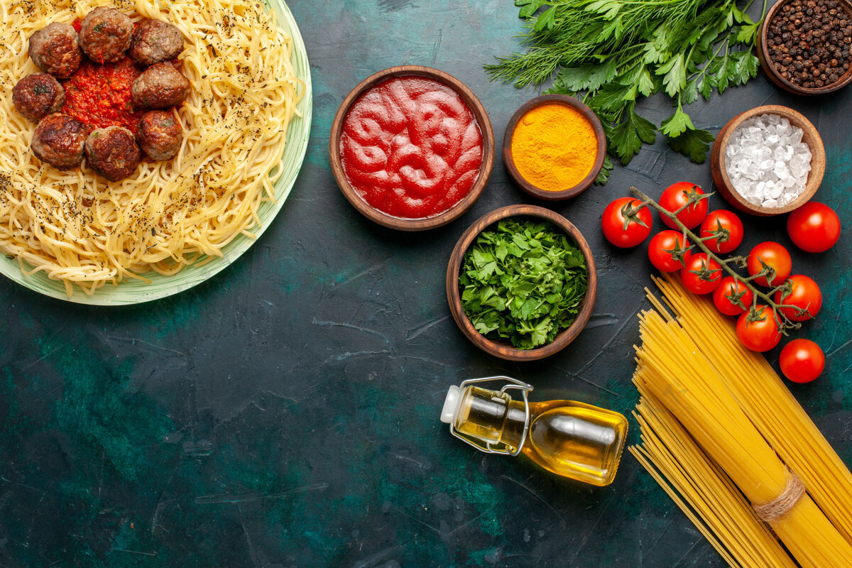 不同俯瞰美味的意大利面食 蓝色背景上有肉丸和不同的调味品面食意大利菜肉