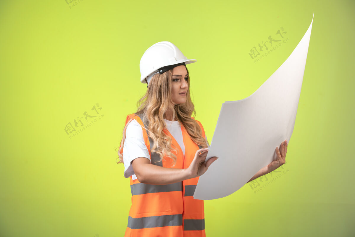 制服戴着白色头盔和装备的女工程师正在检查施工图并阅读它招聘经理团队