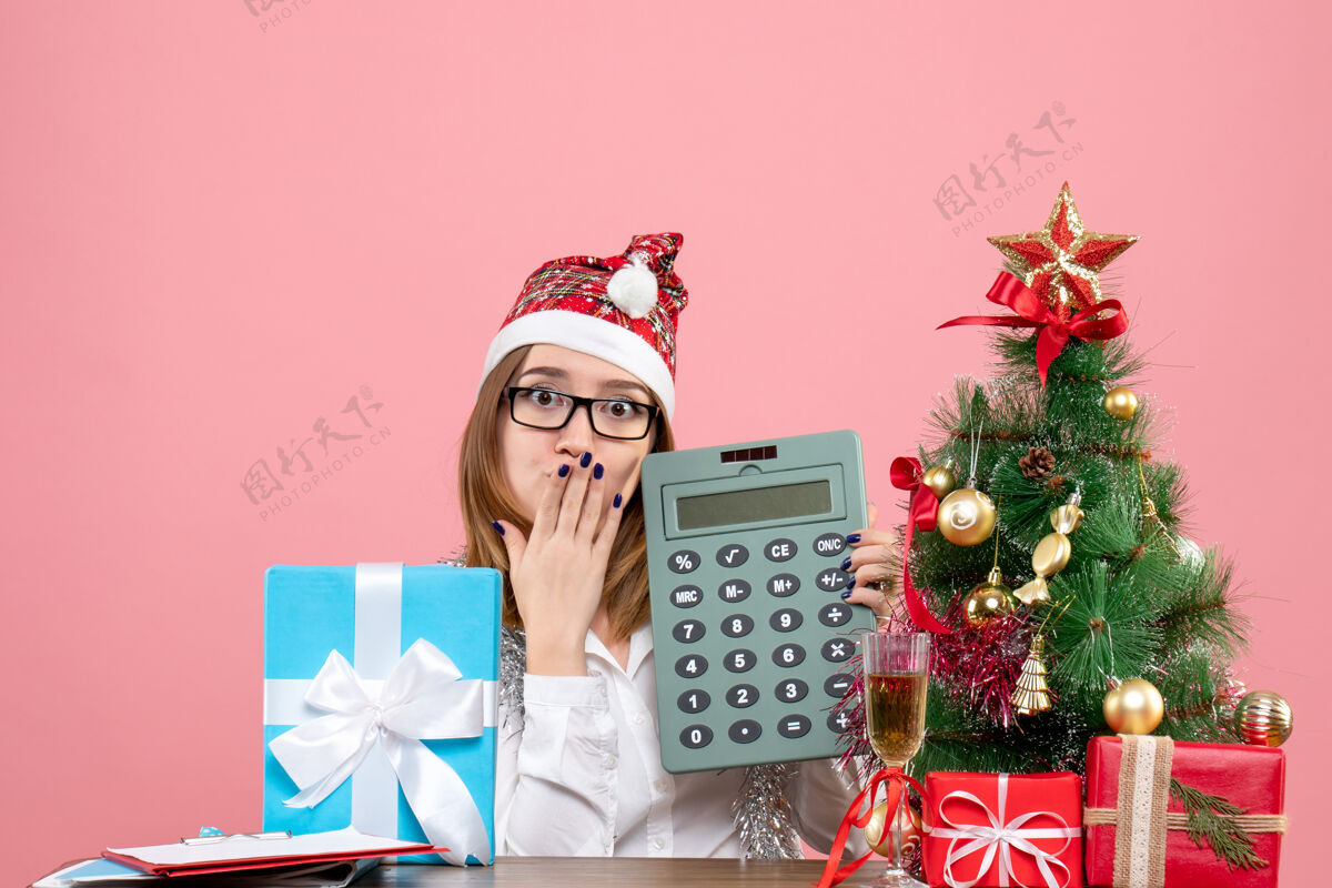 办公室女工手持计算器围着粉色礼物的正视图笔记本电脑金钱工人