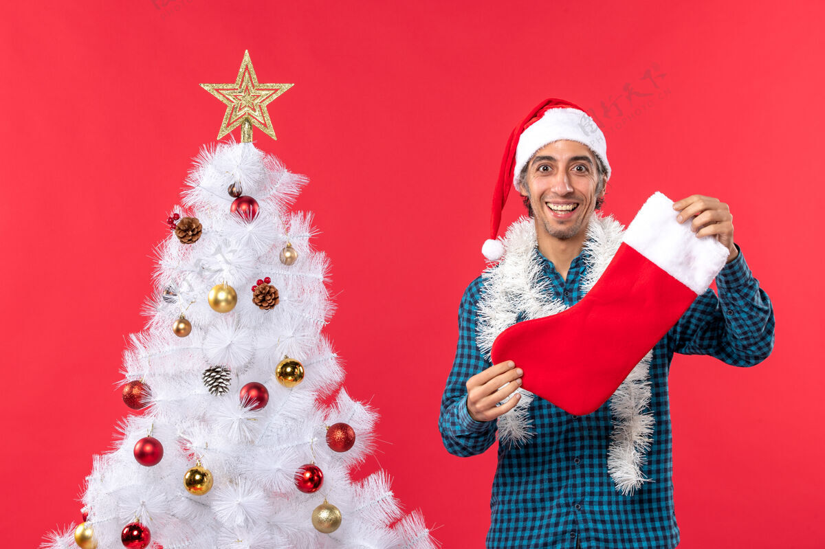 镜头半身镜头的年轻人戴着圣诞老人的帽子 穿着蓝色的衬衫 手里拿着圣诞袜子圣诞老人圣诞一半