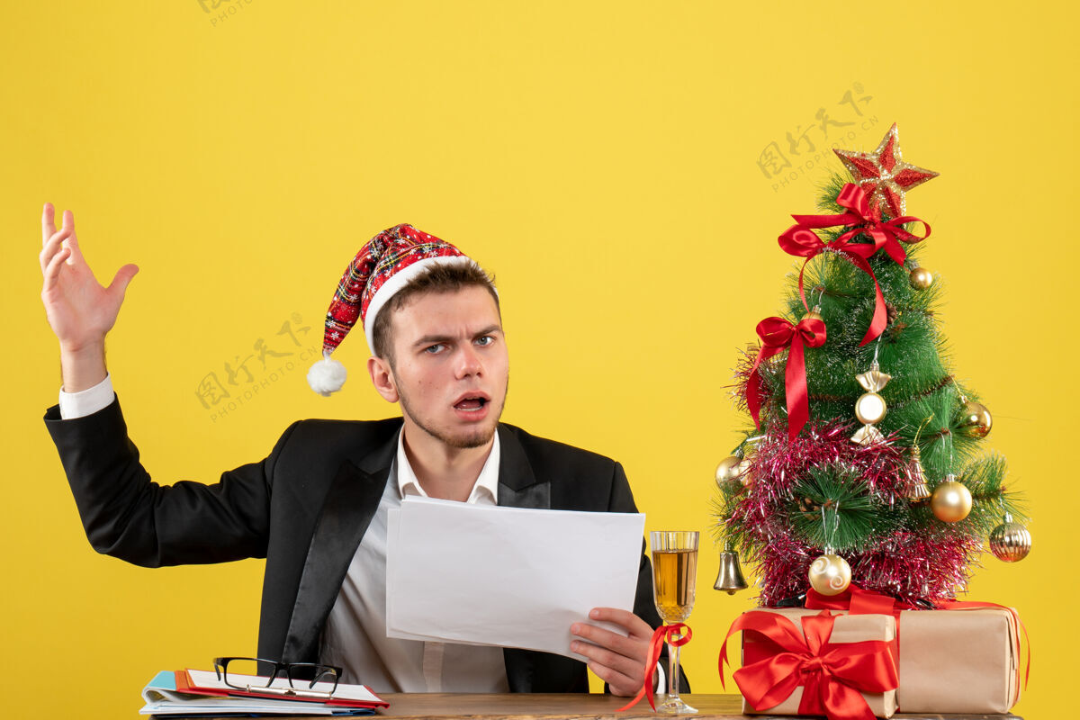 工作正面图男性工人坐在他工作的地方后面拿着黄色的文件坐商人圣诞节
