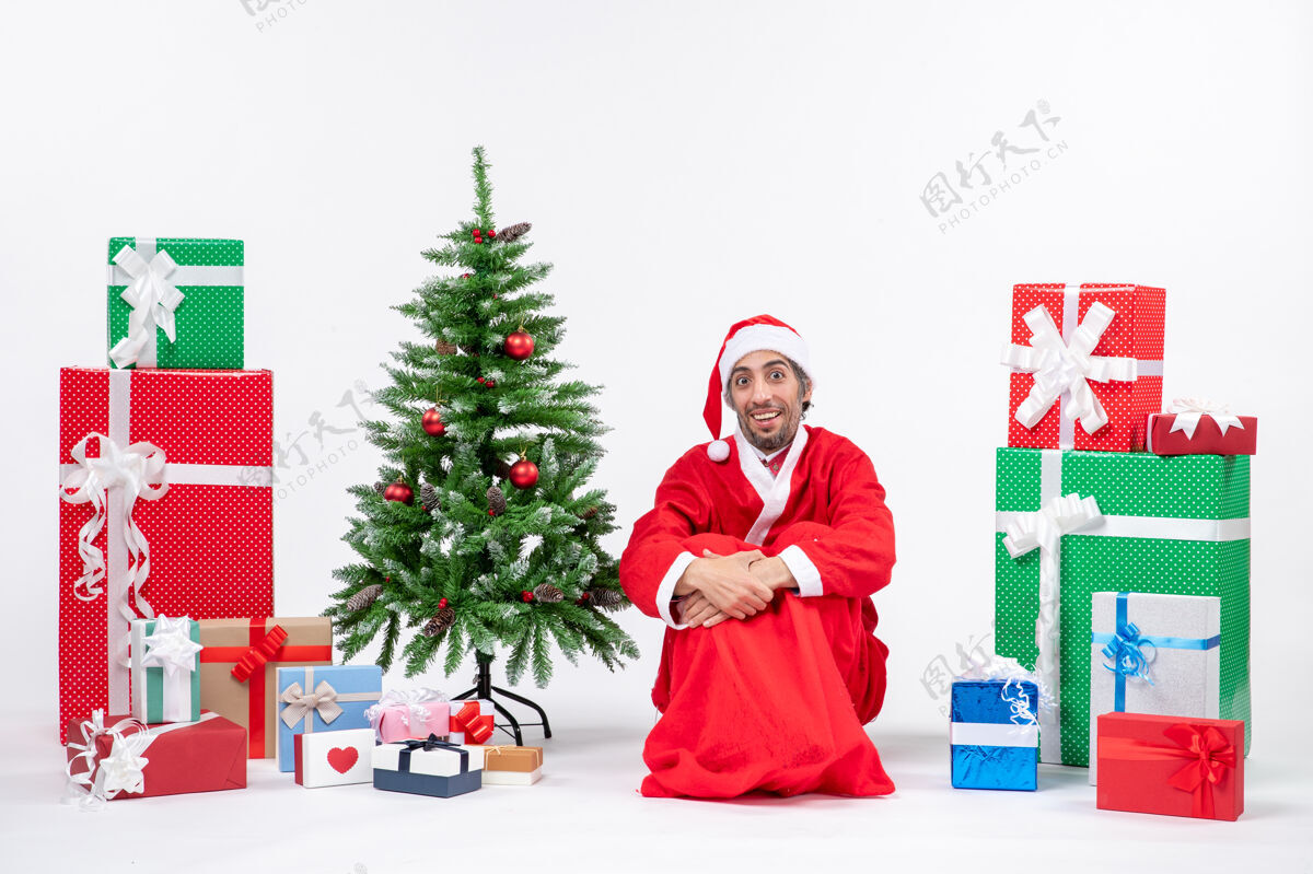 人年轻人打扮成圣诞老人带着礼物和装饰圣诞树圣诞老人打扮礼物