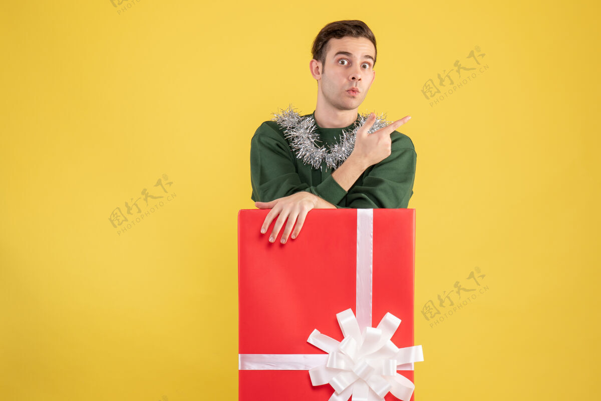 微笑正面图：站在黄色大礼盒后面的年轻人礼品盒购物漂亮