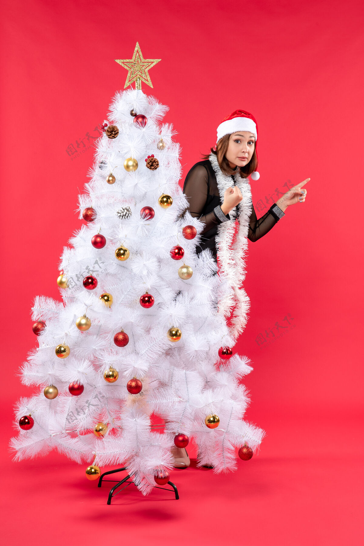 新的圣诞心情与年轻美丽的女士在一个黑色的礼服和圣诞老人的帽子圣诞树新娘圣诞老人