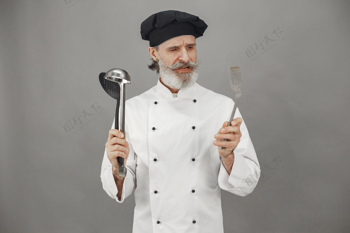 员工高级男子选择勺子厨师头上戴着一顶黑帽子工作工人员工