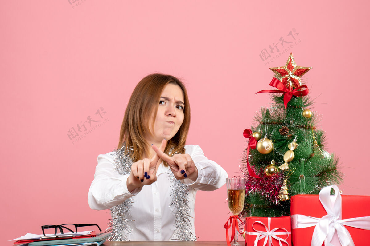 情感女工坐在桌子后面的正面图 粉红色的礼物工作礼物工作