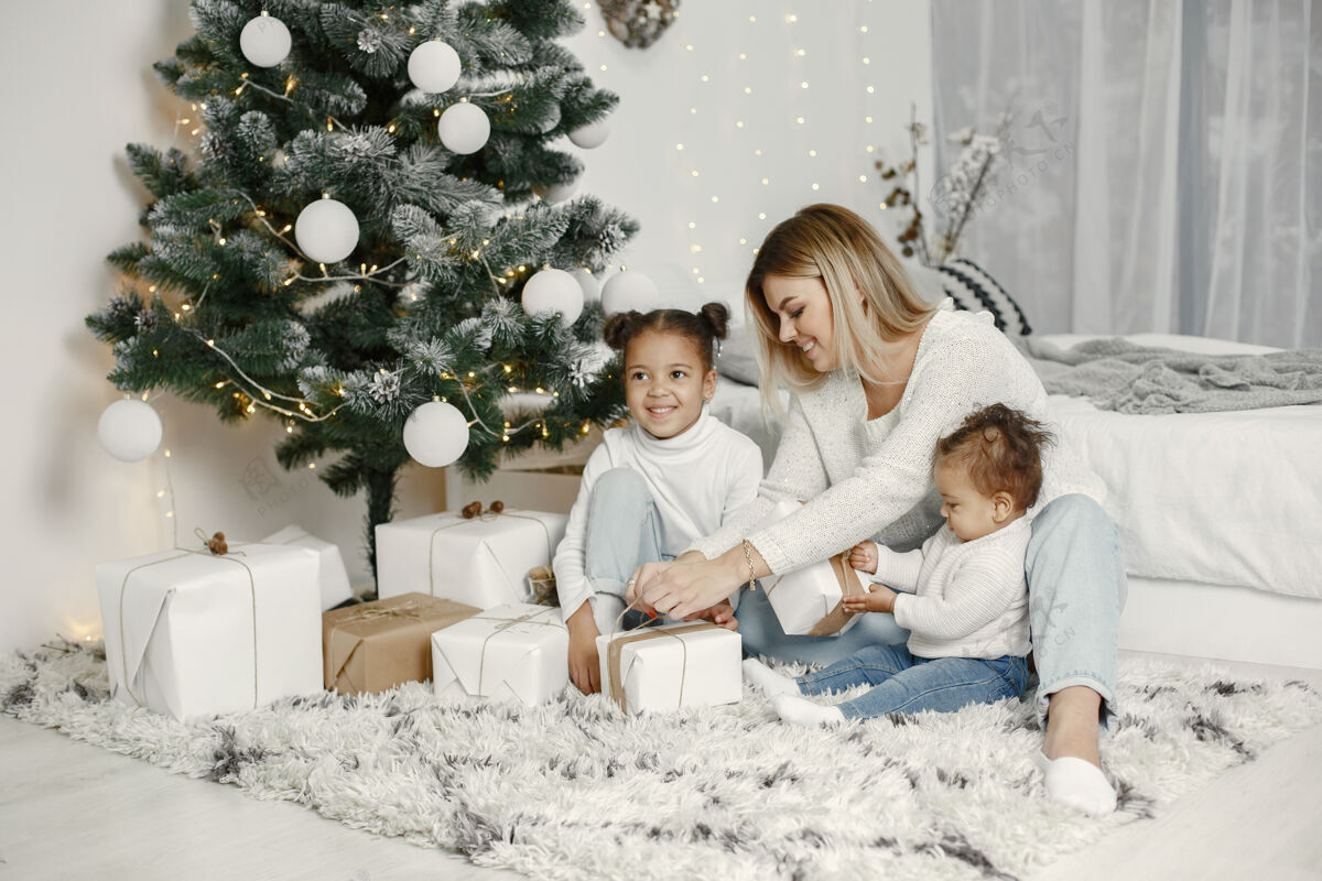 美国人们在为圣诞节做准备母亲在和女儿们玩耍一家人在节日的房间里休息孩子穿着毛衣闪亮传统国际