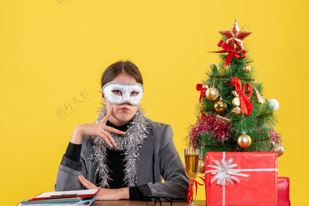 脸颊正面图：戴着面具的女孩坐在桌子旁 手指放着面具坐肖像