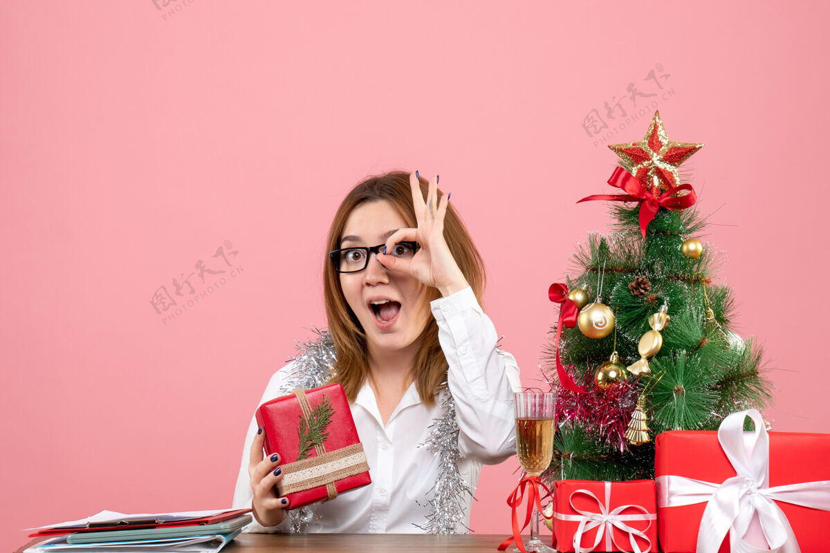 肖像女工围坐在粉红色的圣诞礼物和圣诞树旁的正视图时尚礼物成人
