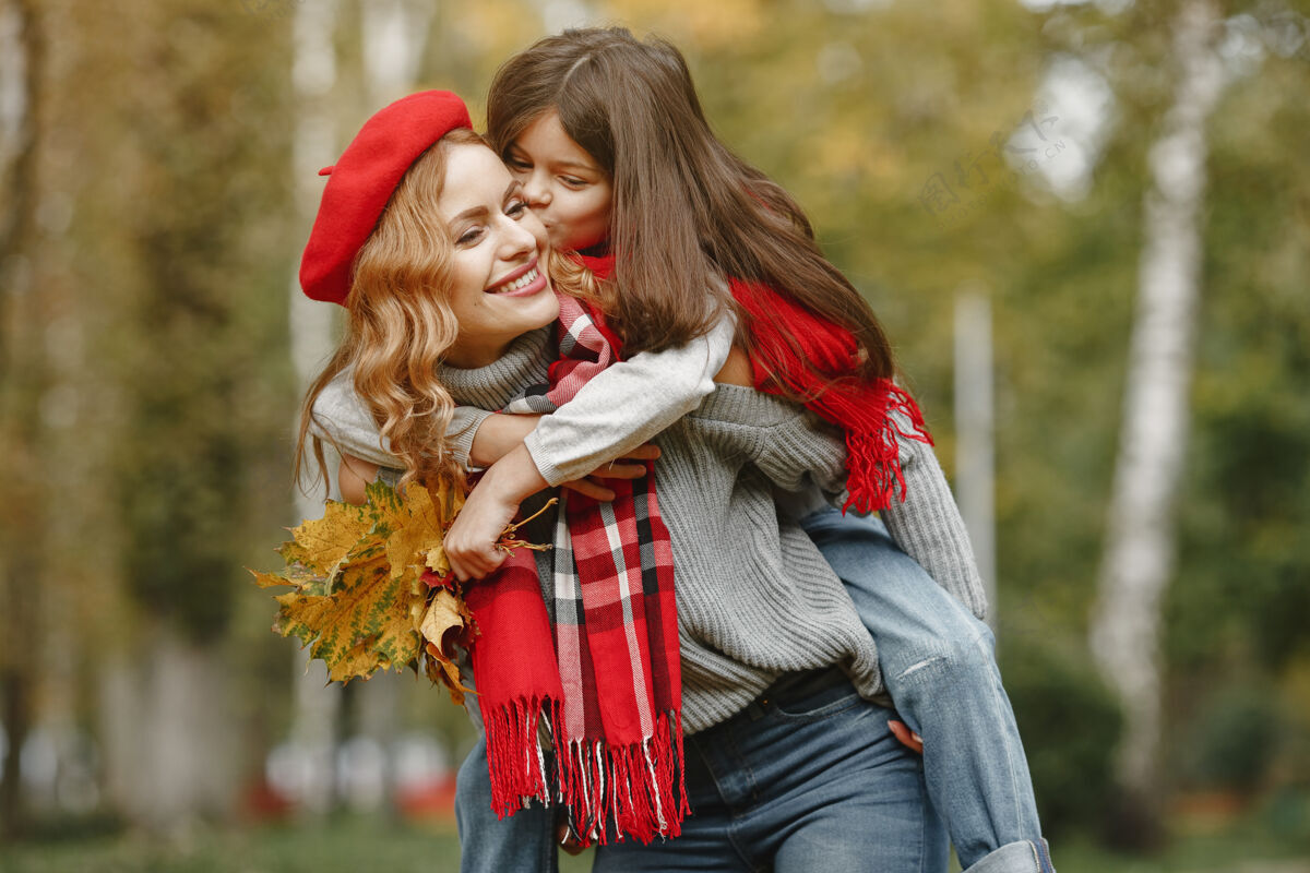 女性时髦的母亲带着女儿黄色的秋天戴着红领巾的女人蓝色快乐快乐