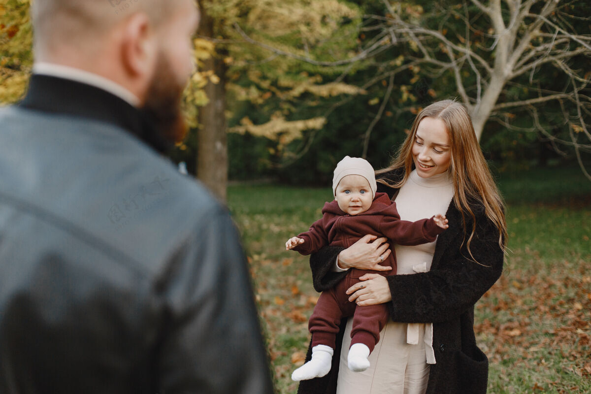 休闲一家人在秋天的公园里男人穿着黑色夹克可爱的小女孩和父母胡须公园女儿