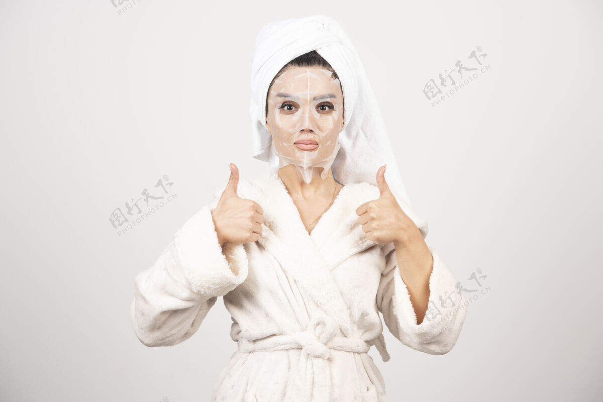 年轻穿着浴衣和带面罩的毛巾的女人皮肤护理面部女士