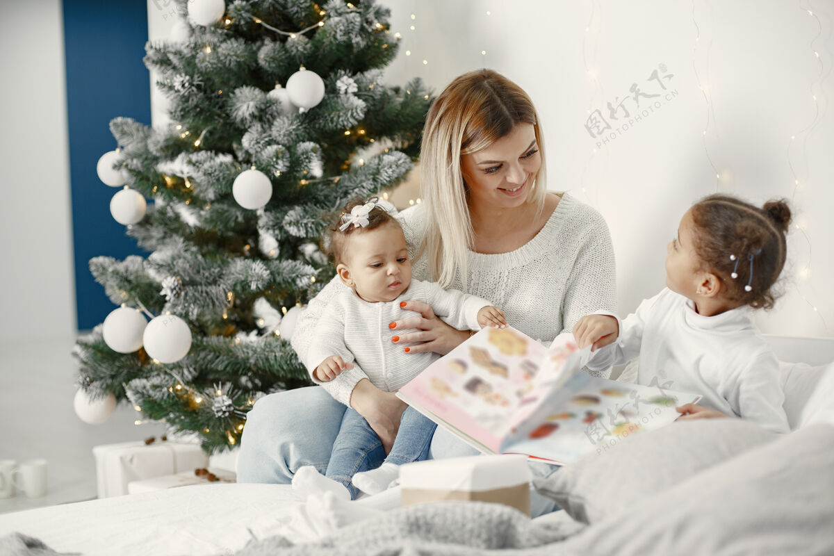 毛衣人们在为圣诞节做准备母亲在和女儿们玩耍一家人在节日的房间里休息孩子穿着毛衣小牛仔裤室内