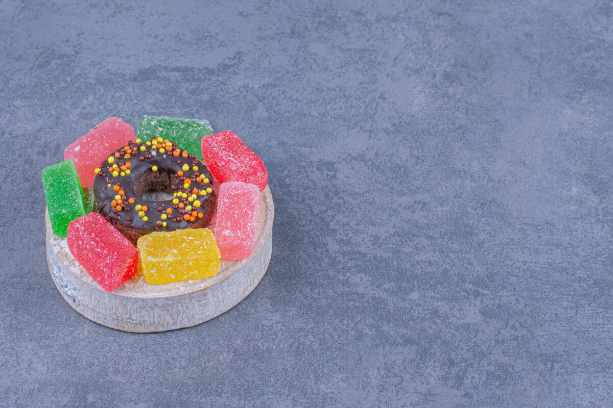 洒美味的甜甜圈和果冻糖果在灰色的表面水果果冻吃
