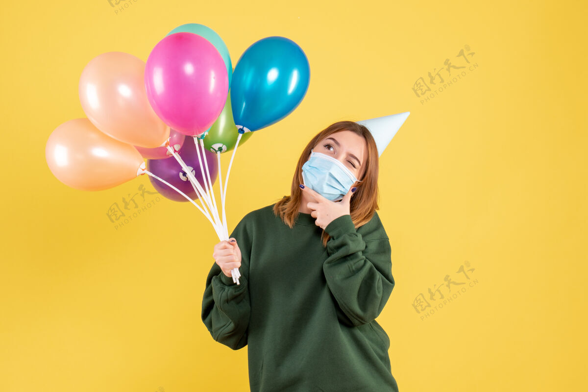 聚会正面图戴面具的年轻女性手持五颜六色的气球气球人庆祝