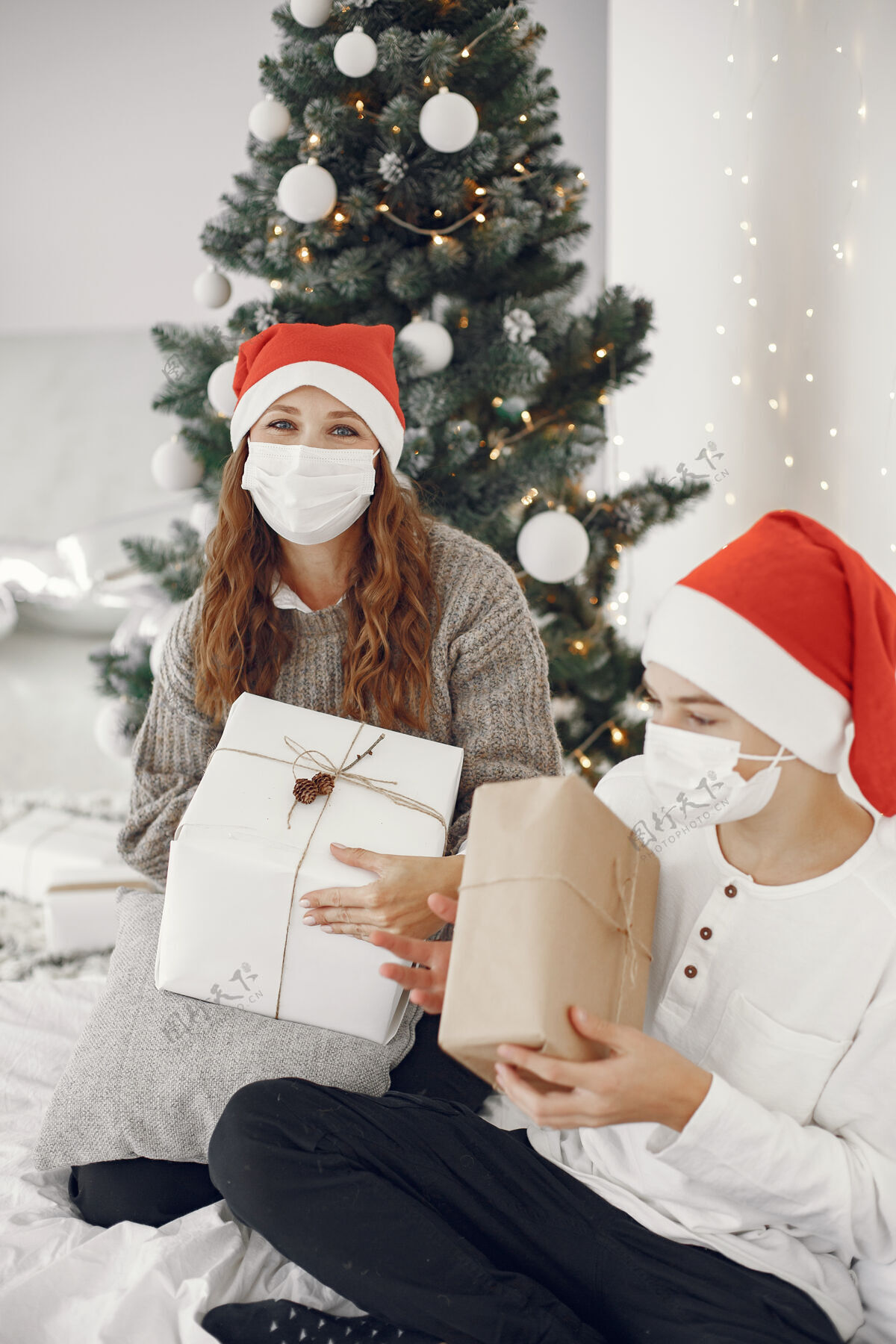 女人为圣诞节做准备的人冠状病毒主题妈妈和儿子玩穿白毛衣的男孩童年盒子黑发