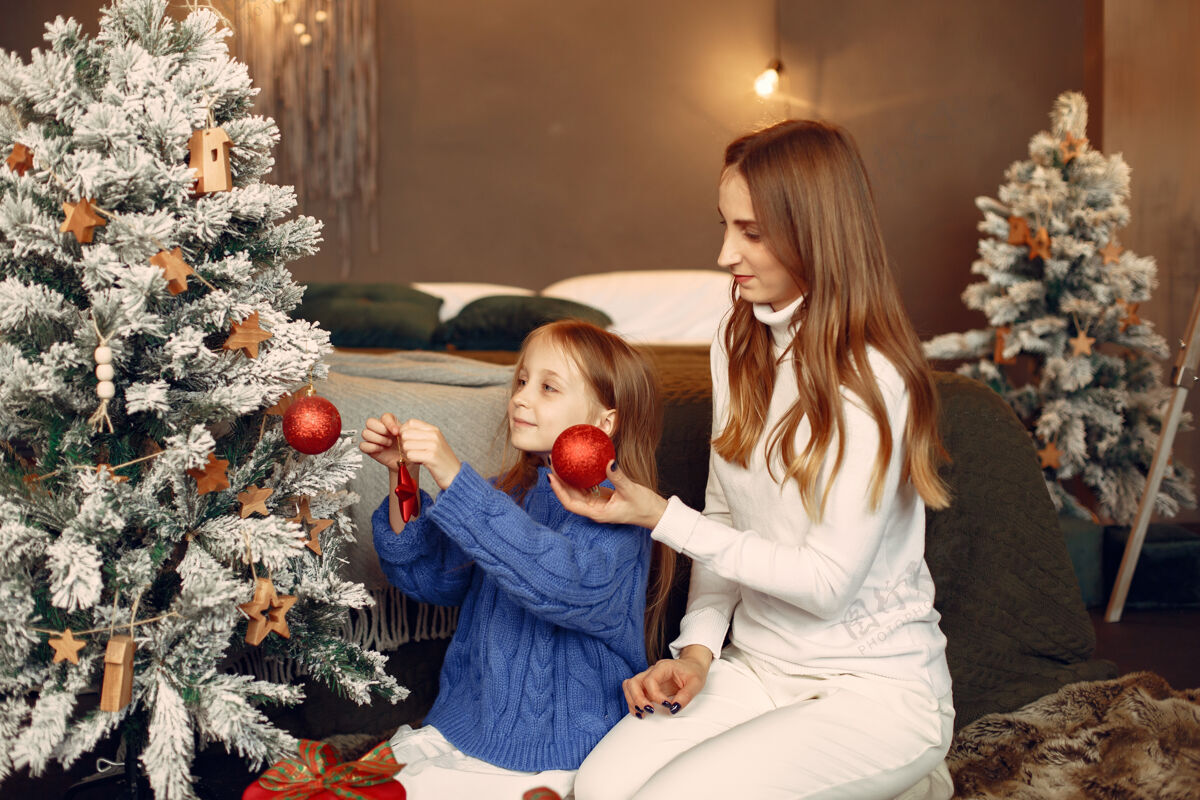 玩具人们在为圣诞节做准备母亲在和女儿玩耍一家人在节日的房间里休息孩子穿着蓝色毛衣杉木绿色装饰