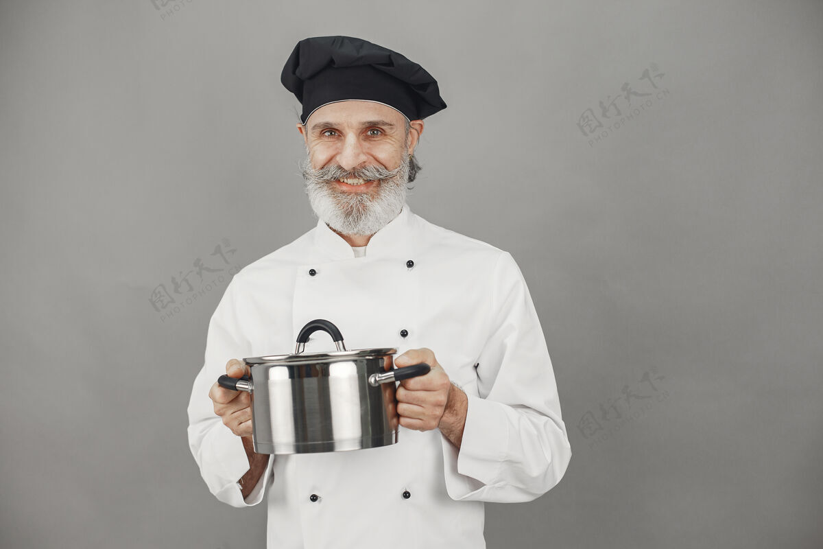 人戴着金属锅的高级男人戴着黑帽子的厨师员工灰色美食家