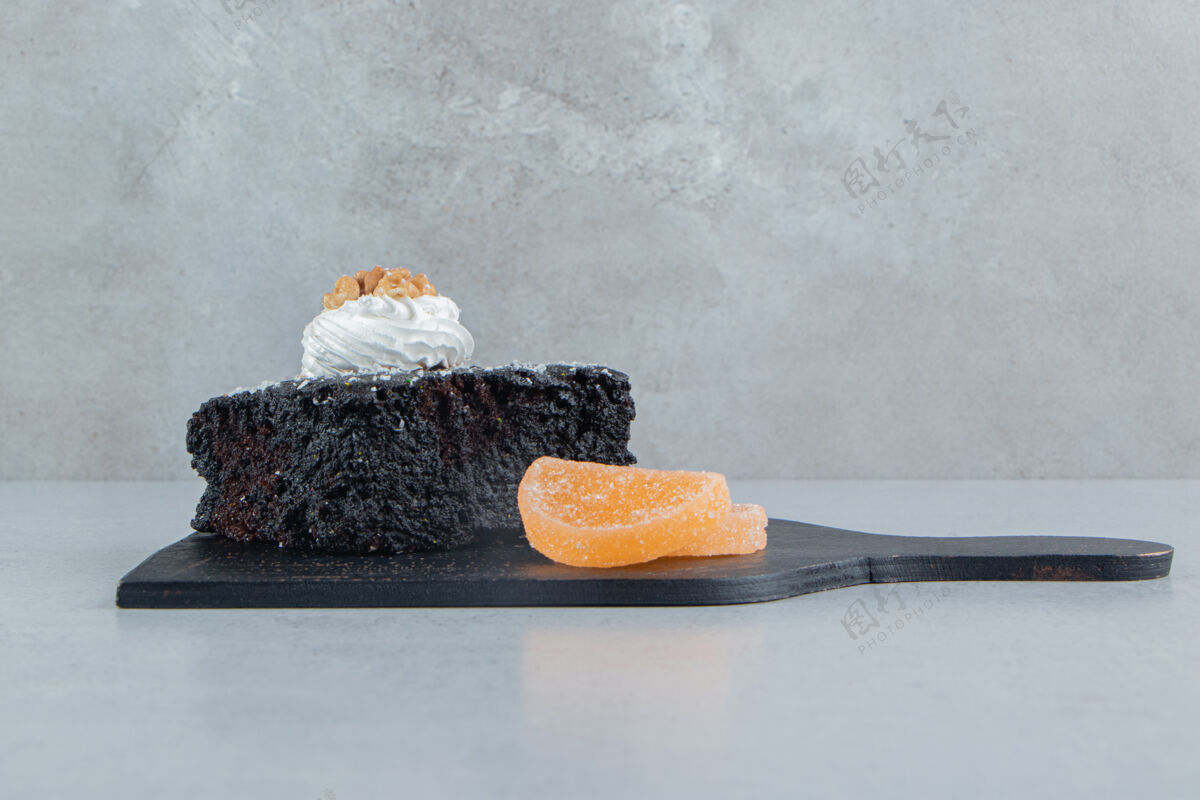 核桃巧克力蛋糕和果酱放在大理石背景的黑木板上果酱烘焙配料