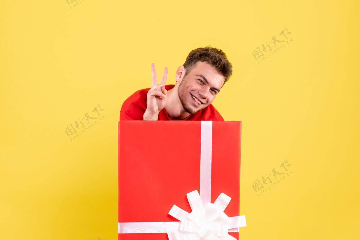 颜色正面图身着红衫的年轻男子站在礼物盒内微笑着圣诞节节日年轻男性