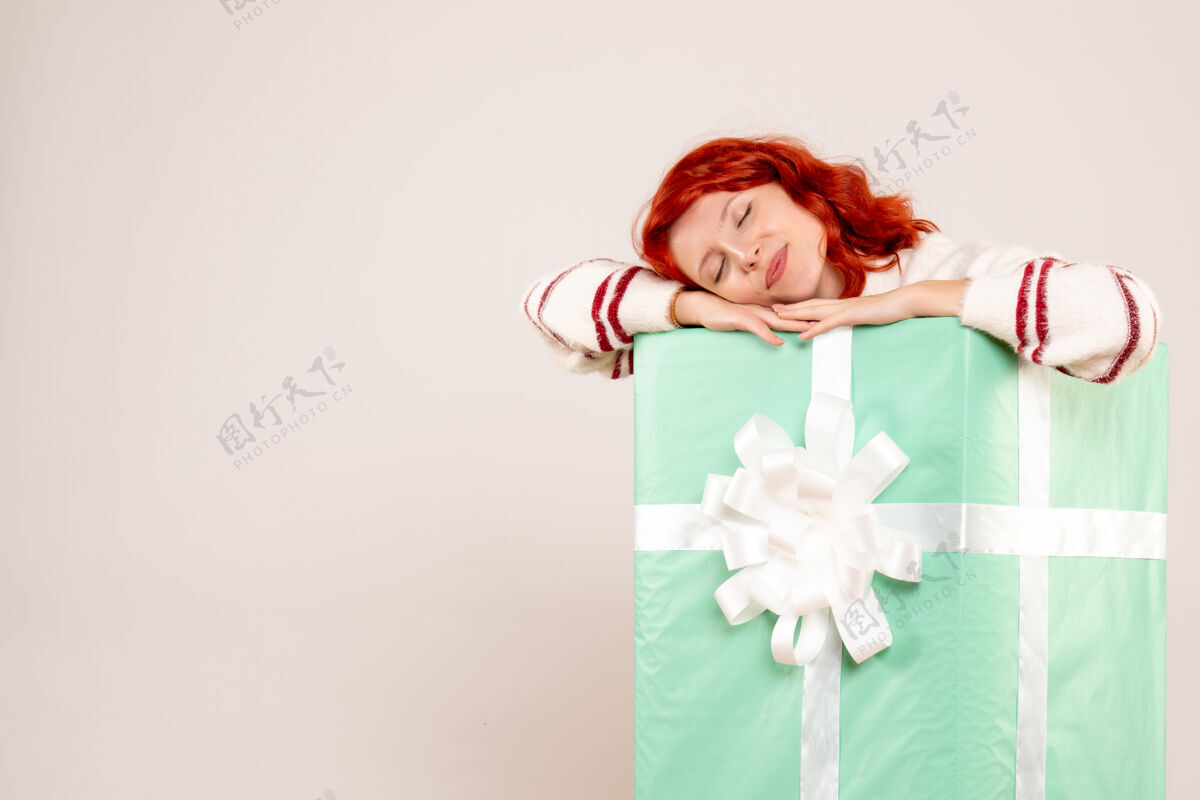 快乐年轻女子躲在圣诞礼物里睡在白墙上的前视图盒子节日微笑