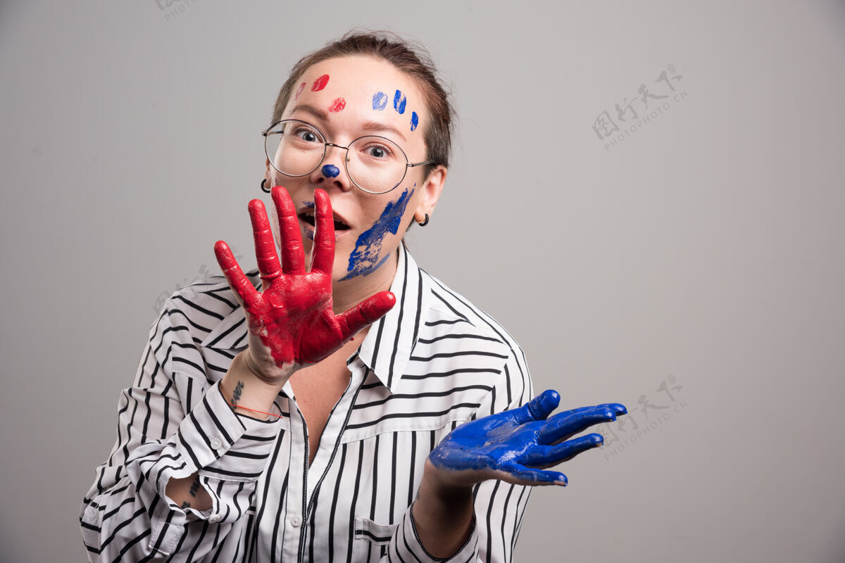 画一个在灰色背景下脸上画着颜料的女人画明亮艺术家