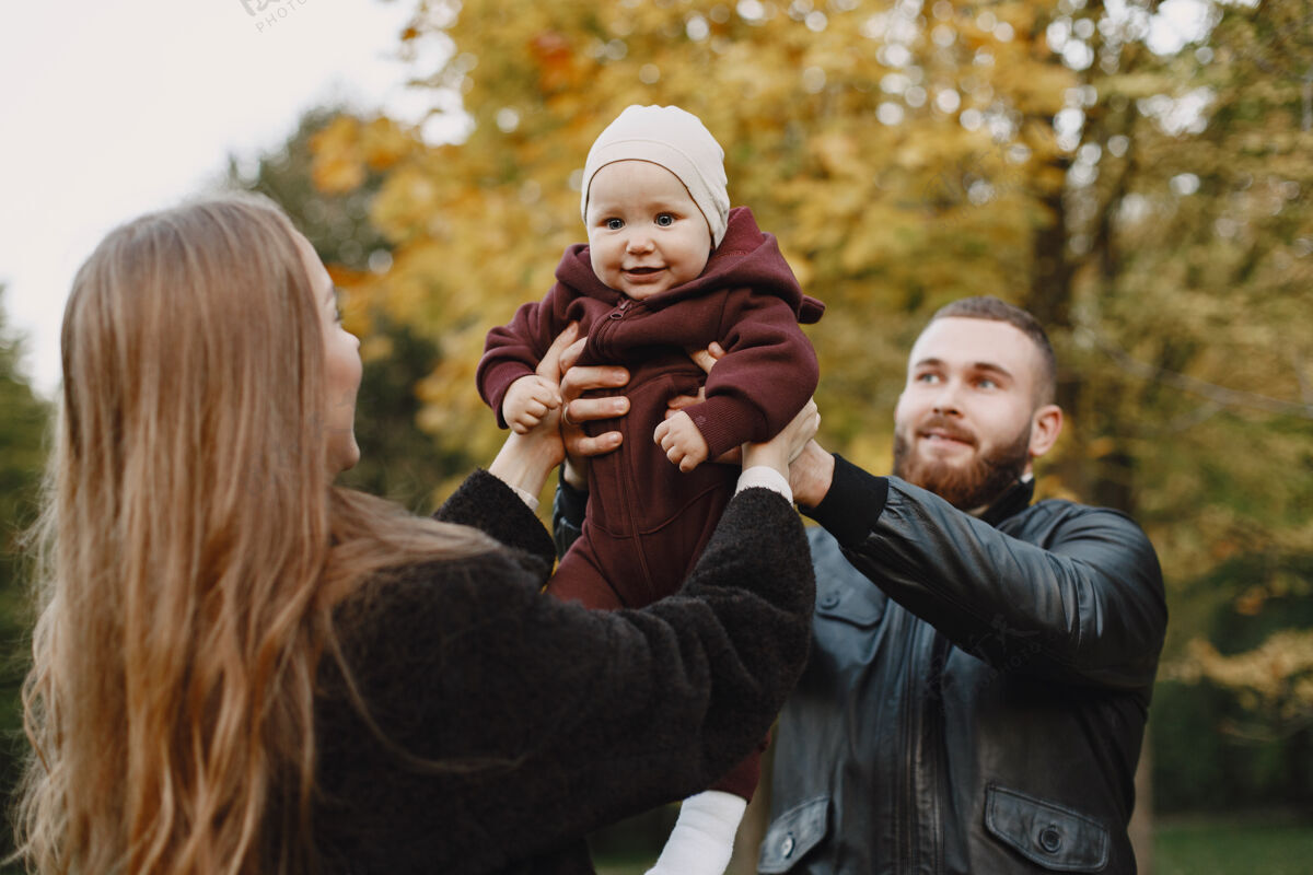 父母一家人在秋天的公园里男人穿着黑色夹克可爱的小女孩和父母孩子女儿黑发