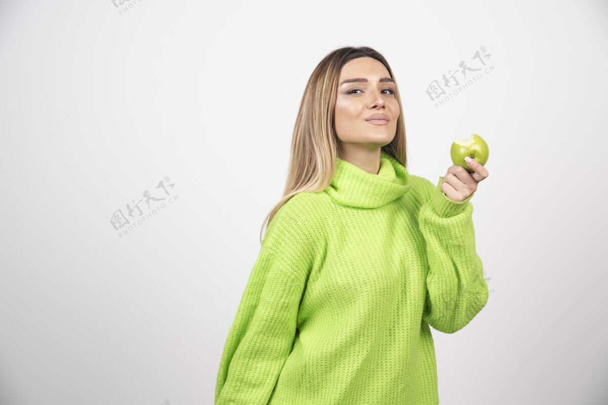 表情穿着绿色t恤的年轻女子手里拿着一个苹果人吃健康