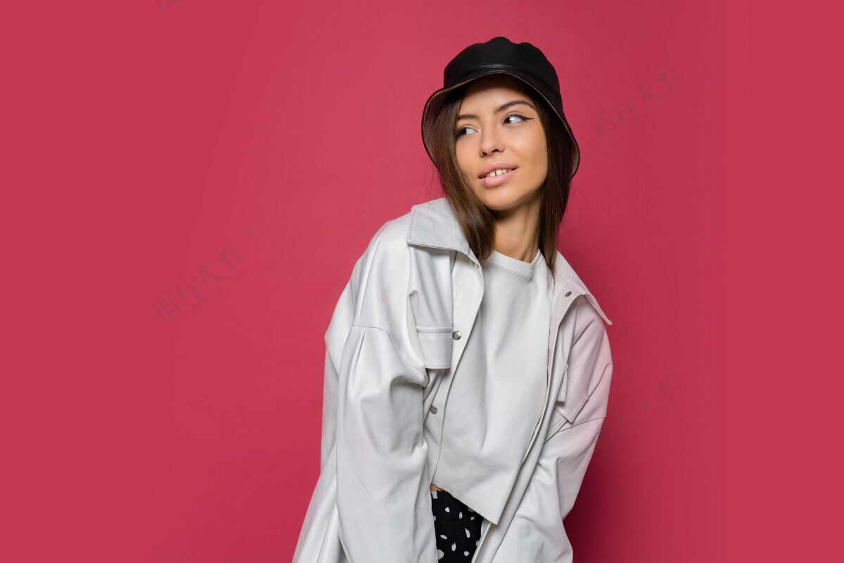 站立特写摄影棚美丽女子的肖像 完美的微笑 戴着时髦的帽子和白色夹克 在粉色背景下摆姿势孤立女人室内粉色